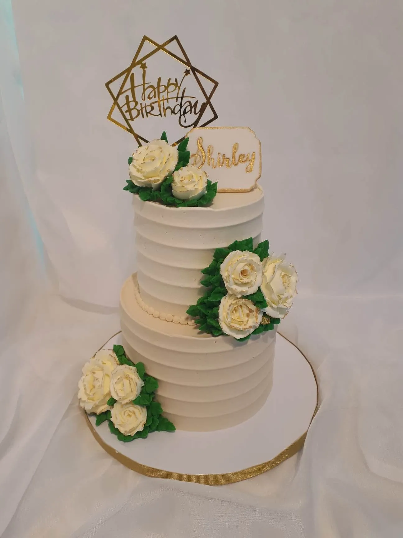 Two-tier white birthday cake with cream roses