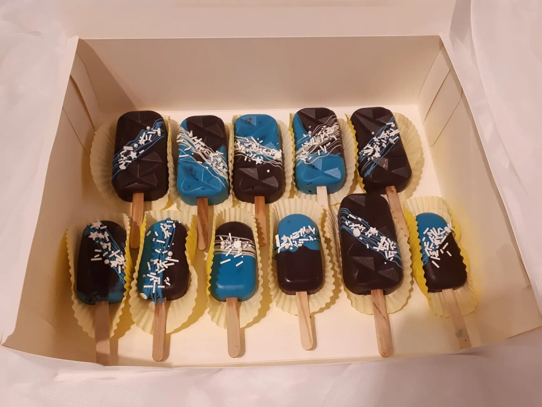 Blue and chocolate cakesicles in a box
