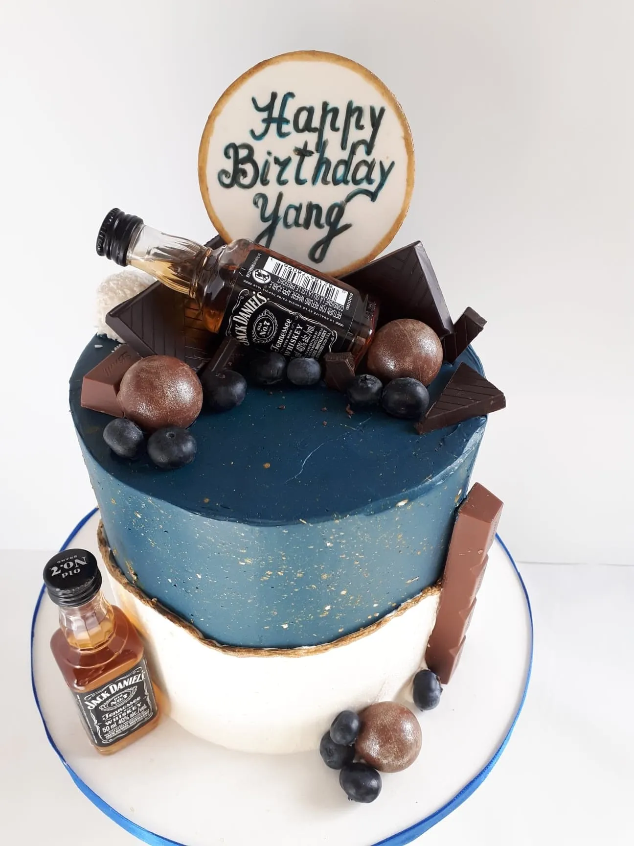 Blue birthday cake with mini whisky bottles and chocolates