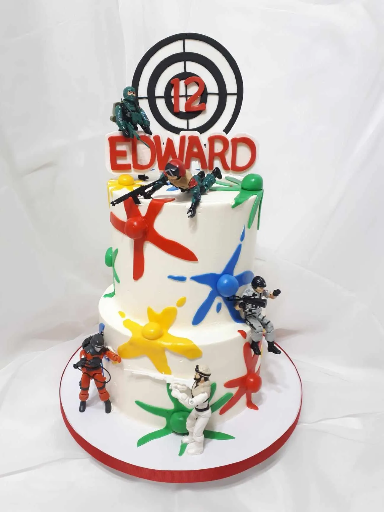 Paintball birthday cake with paint splashes and figurines