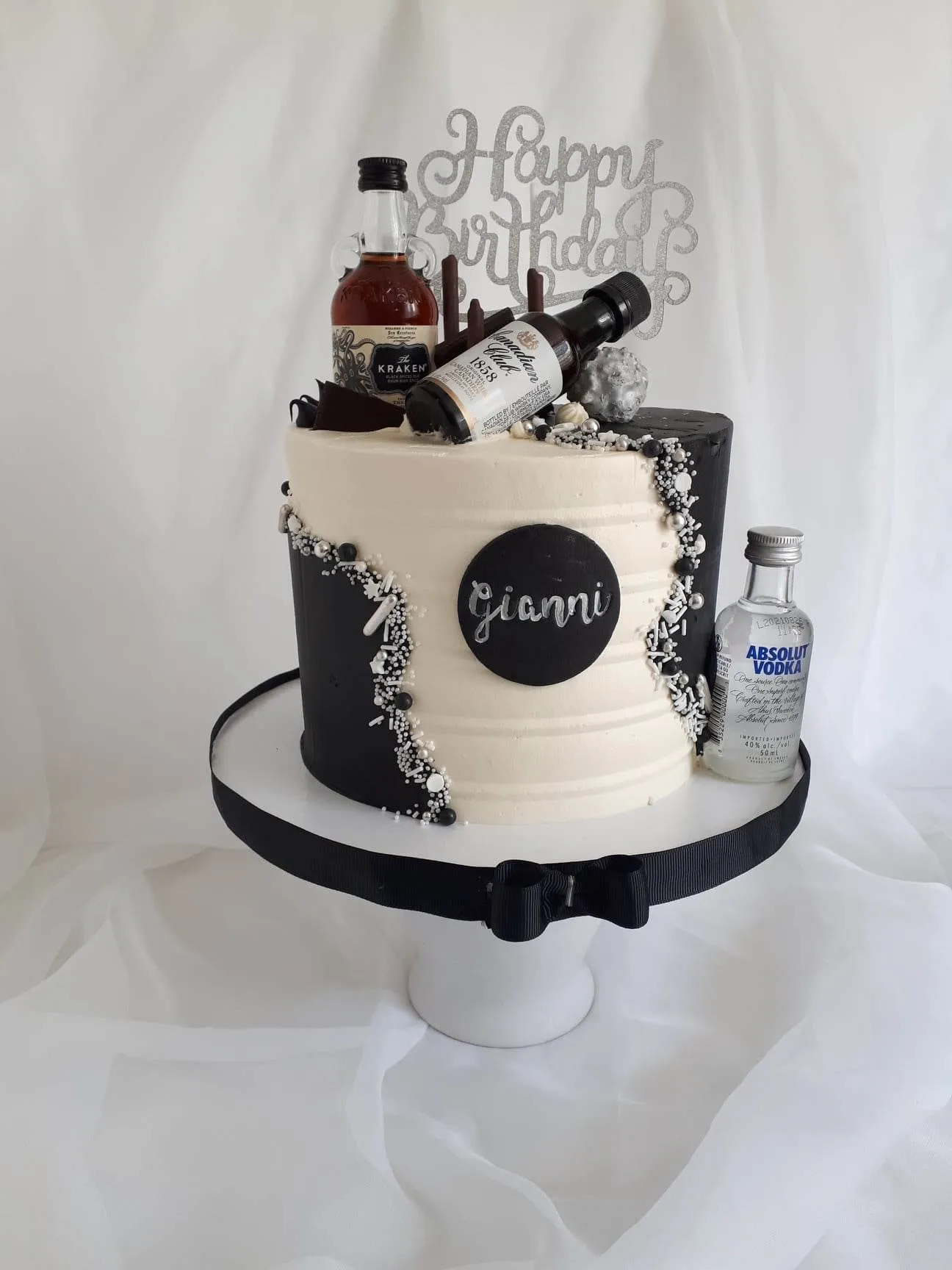 Black and white birthday cake with mini vodka and whisky bottles